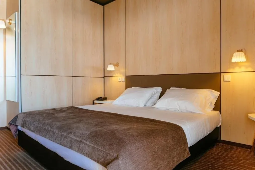 Cama confortável em quarto de hotel comVermar | Axis Hotéis & Golfe | Website Oficial e iluminação suave.
