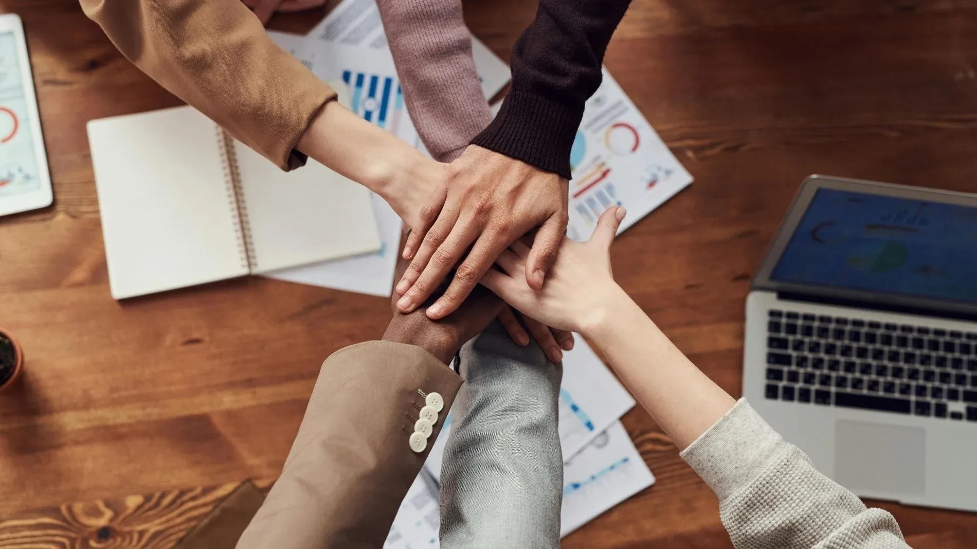 un groupe de personnes met leurs mains ensemble sur une table en bois