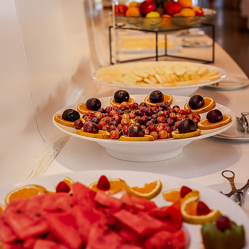 Axis: Corporate: Mesa de buffet con frutas frescas, uvas, naranjas, sandía y piña.