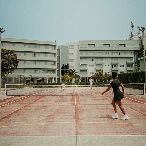 two people are playing tennis in front of a large building