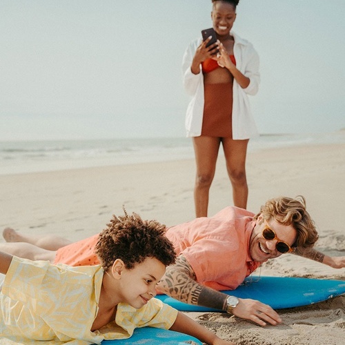 a man with a tattoo on his arm is laying on a surfboard on the beach
