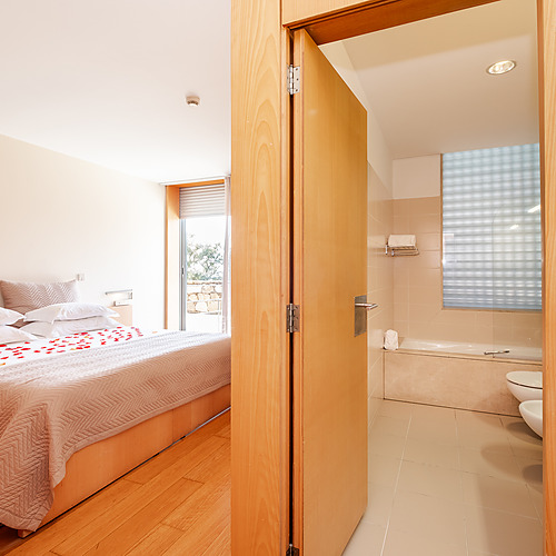 Suite con cama matrimonial decorada con pétalos, baño con tina y bidé. Axis: Corporate