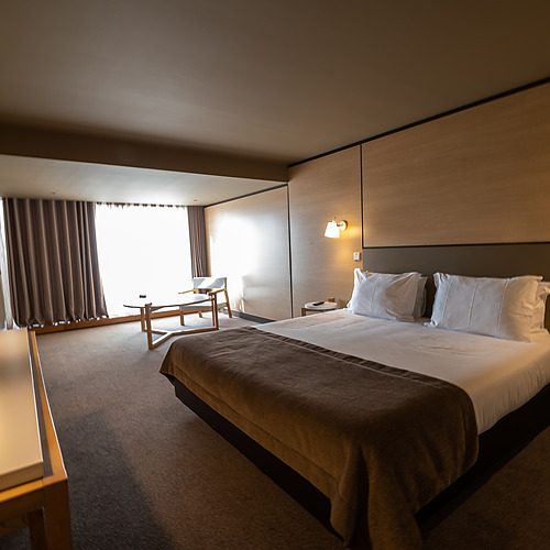 Quarto de hotel moderno com cama confortável,Axis: Corporate e área de estar com vista para a janela.