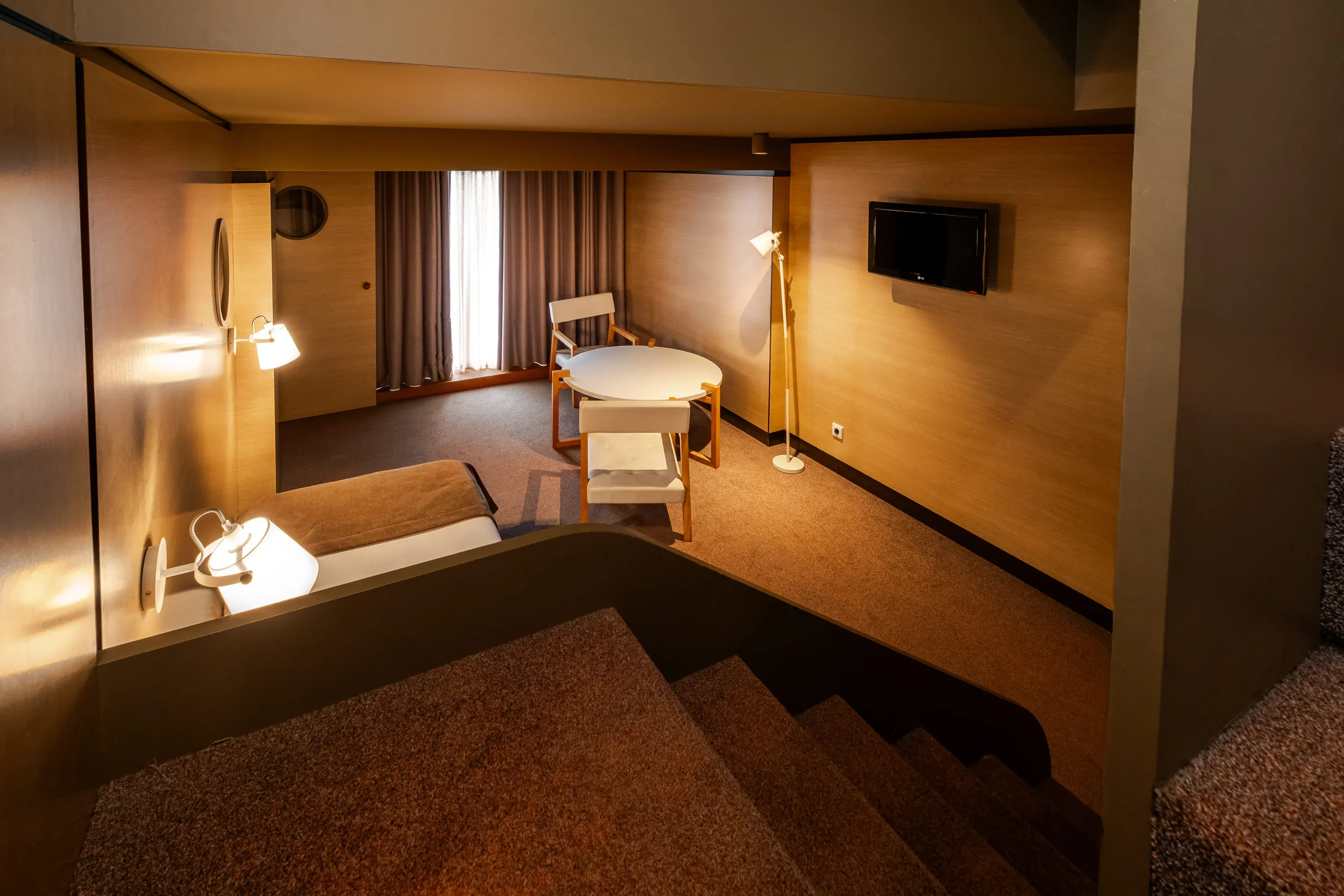 Quarto de hotel moderno com mesa, cadeiras e TV, ideal para Vermar | Axis Hotéis & Golfe | Website Oficial.