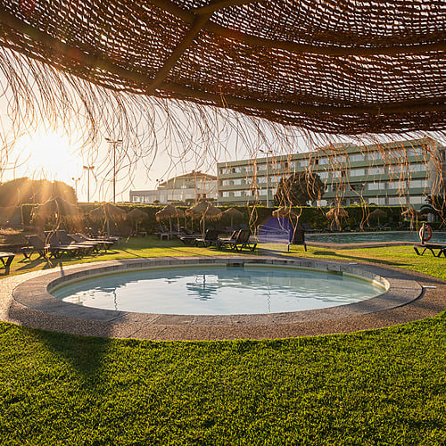 Piscina del hotel y tumbonas bajo un atardecer soleado. Axis: Corporate