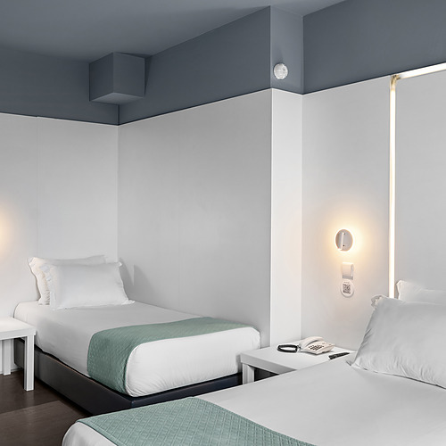 Habitación con dos camas individuales, ideal para familias. Axis: Corporate con estilo moderno y luz cálida.