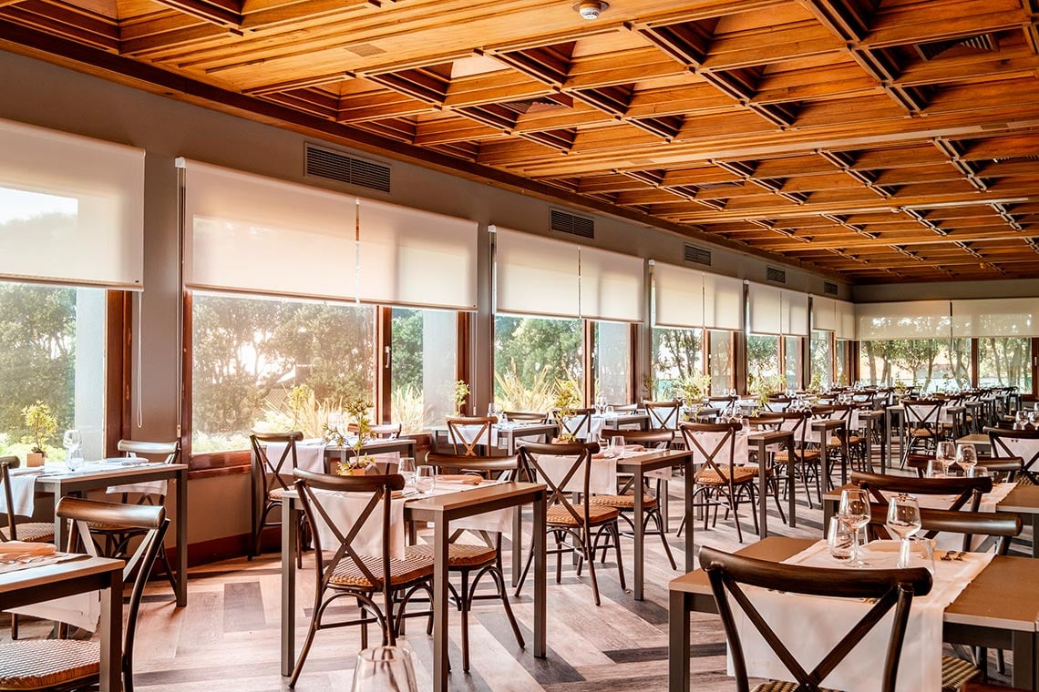 Sala de jantar do hotel com mesas postas e vista para o exterior, ideal para Vermar | Axis Hotéis & Golfe | Website Oficial.