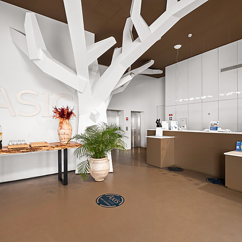 Recepción de hotel moderno con arte de árbol abstracto y oferta de bebida de bienvenida. Axis: Corporate