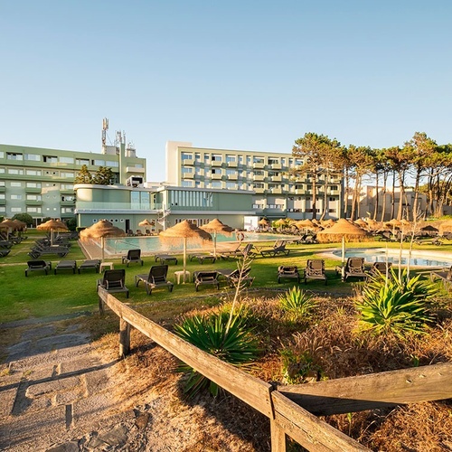 a large hotel with a swimming pool surrounded by chairs and umbrellas