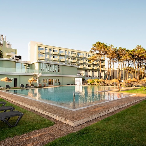 a large hotel with a large swimming pool in front of it