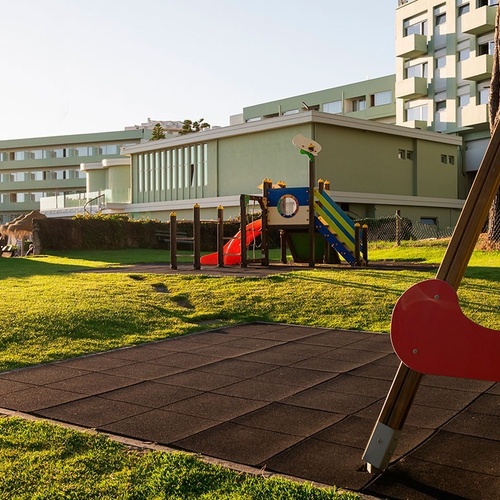 a playground with a slide and swings in front of a building