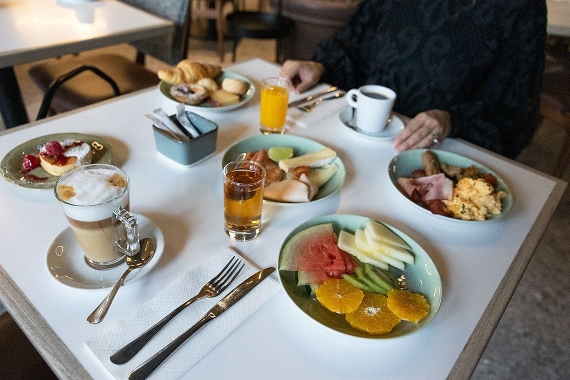 a woman sits at a table with plates of food and drinks