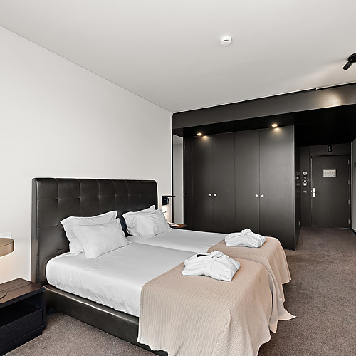 Quarto de hotel com duas camas, roupões e móveis modernos. Axis: Corporate