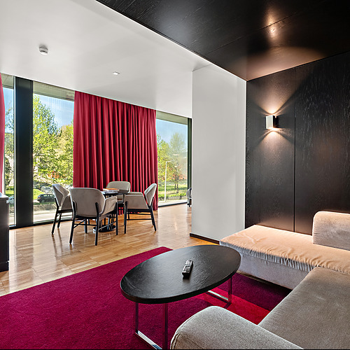 Sala de estar moderna em hotel com sofá, mesa de centro e janela ampla com vista para o exterior. Axis: Corporate