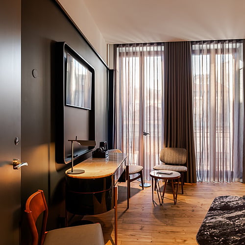 Quarto de hotel moderno com mesa de trabalho, TV e cama. Axis: Corporate