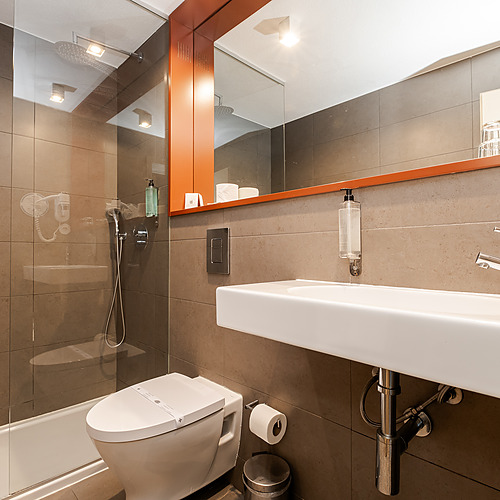 Baño moderno y limpio con ducha, inodoro y lavabo. Axis: Corporate