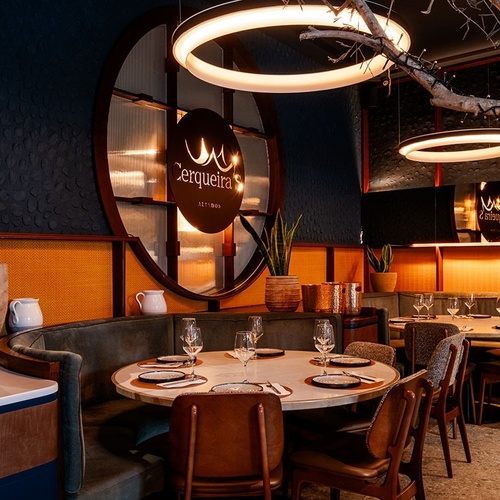 The inviting interior of a modern restaurant features elegant circular lighting fixtures, dark and warm tones, and neatly set dining tables, highlighted by a prominent 