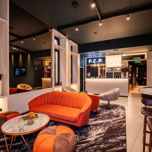 This image captures a chic and modern lounge space featuring a vibrant orange sofa, a sleek bar with an 