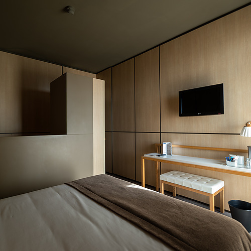 Quarto de hotel moderno com cama, escrivaninha e TV. Axis: Corporate