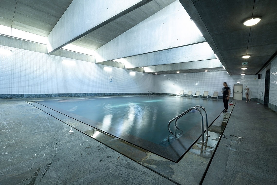 a large indoor swimming pool with a person standing on the edge