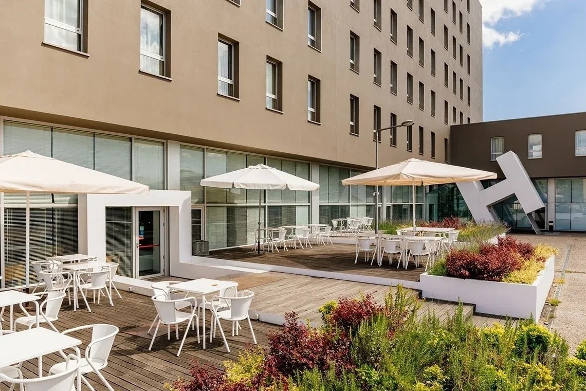 una terraza con mesas y sillas y paraguas frente a un edificio