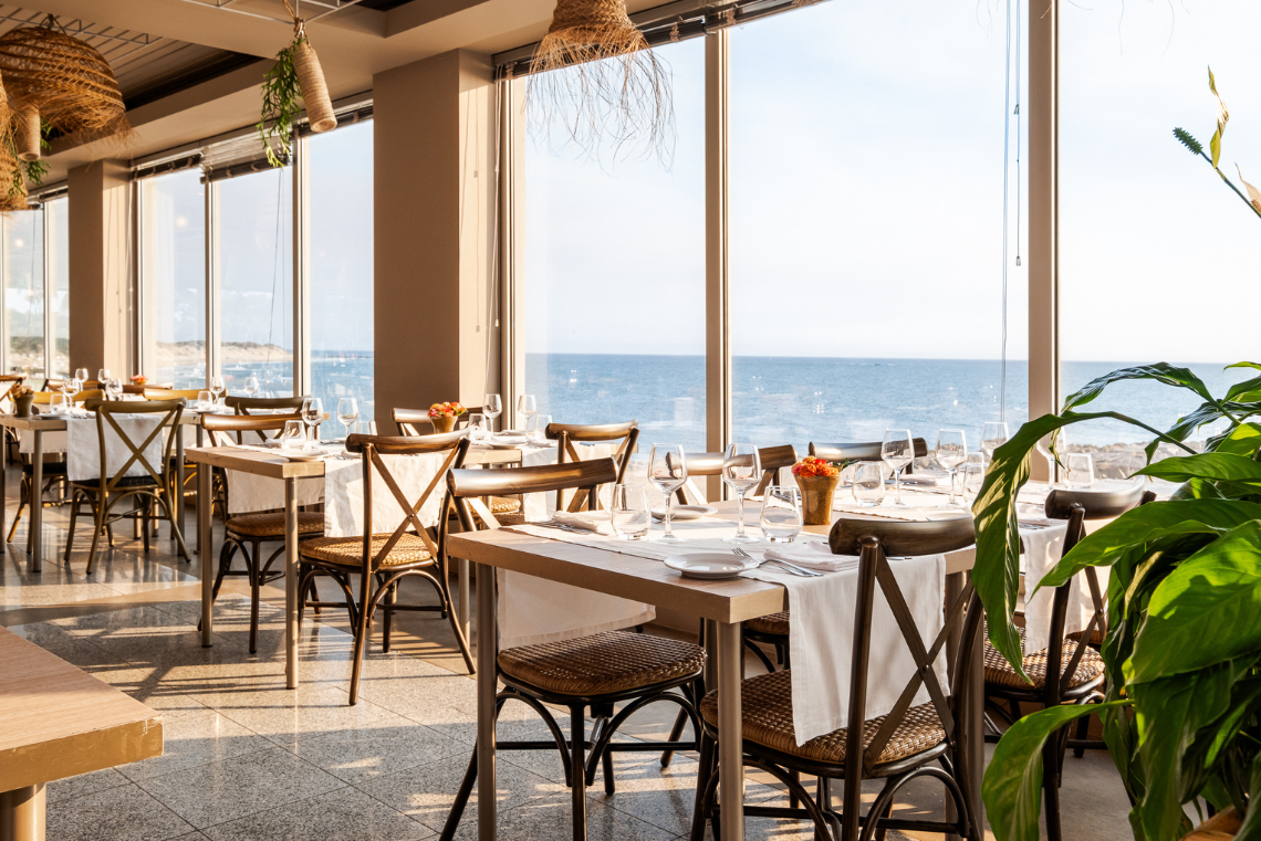 mesas e cadeiras em um restaurante com vista para o oceano