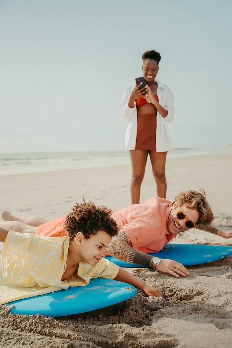 um homem e um menino estão deitados em pranchas de surf na praia