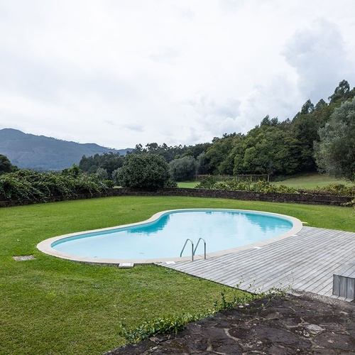 a large swimming pool surrounded by grass and trees with mountains in the background