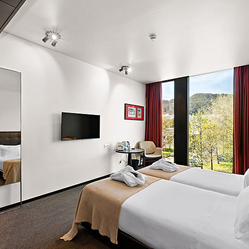 Quarto duplo moderno com vista para a paisagem, espelho grande e TVs planas. Axis: Corporate