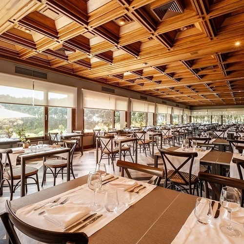 a restaurant filled with tables and chairs with a wooden ceiling