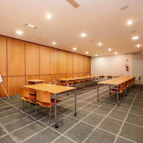 Sala de conferencias moderna con mesas, sillas y rotafolio, ideal para Axis: Corporate.