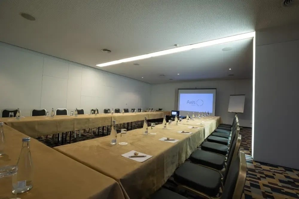 une salle de conférence avec des tables et des chaises et un projecteur avec le logo axis