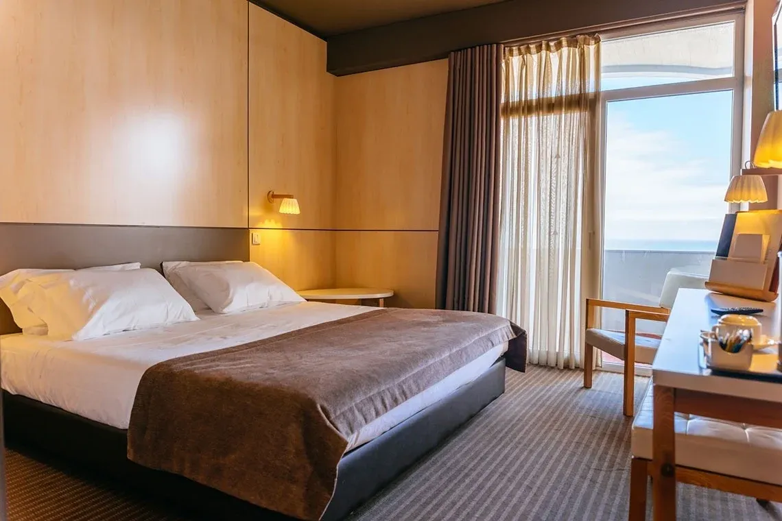 Quarto de hotel com vista para o mar, com cama, candeeiro e varanda. Vermar | Axis Hotéis & Golfe | Website Oficial