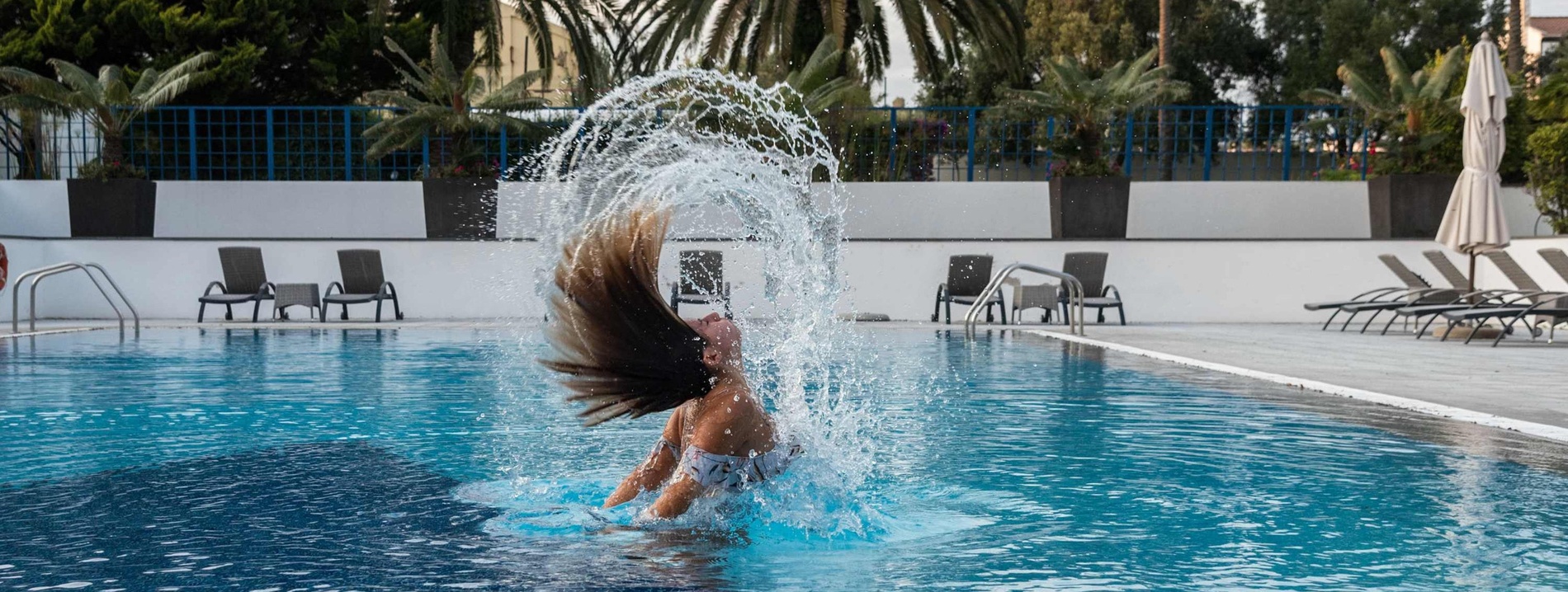 a woman is splashing her hair in a swimming pool