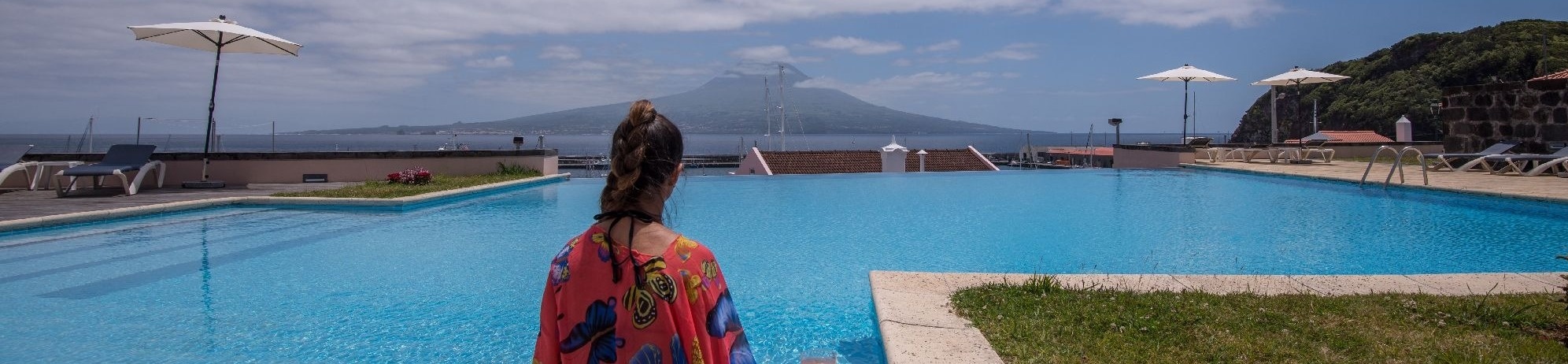 una mujer se sienta en el borde de una piscina con una copa de champán en la mano