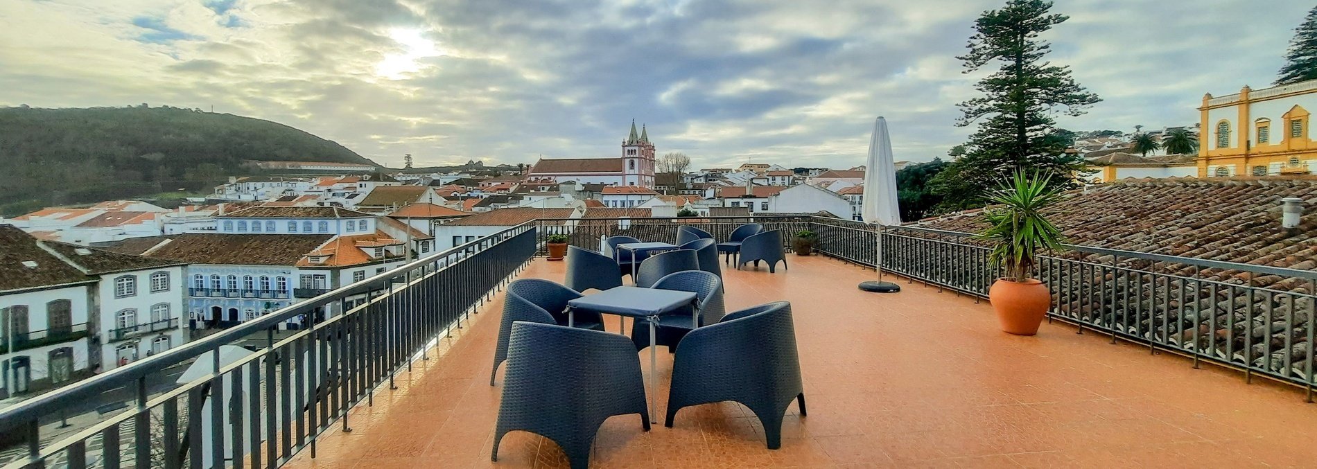 a balcony with tables and chairs overlooking a city