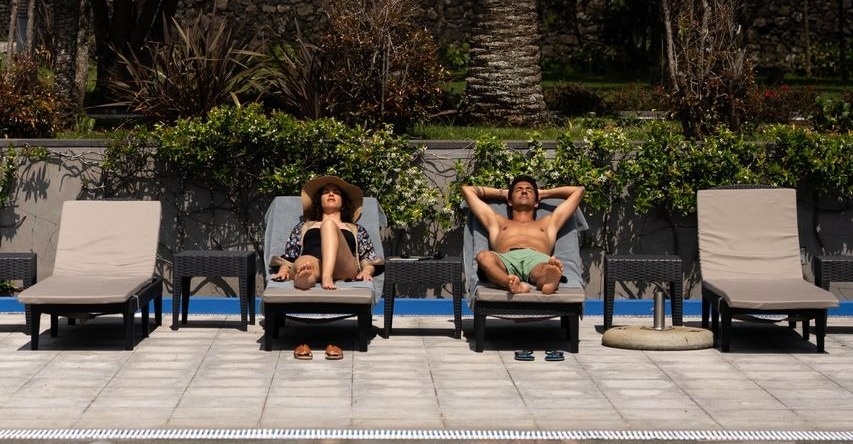 dos personas se relajan en tumbonas junto a una piscina