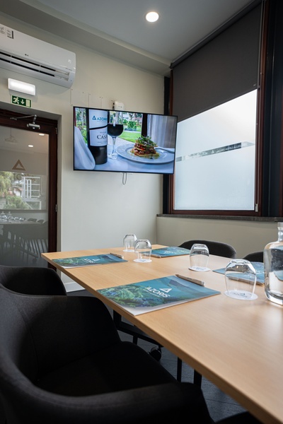 uma sala de conferências com uma mesa longa e cadeiras brancas
