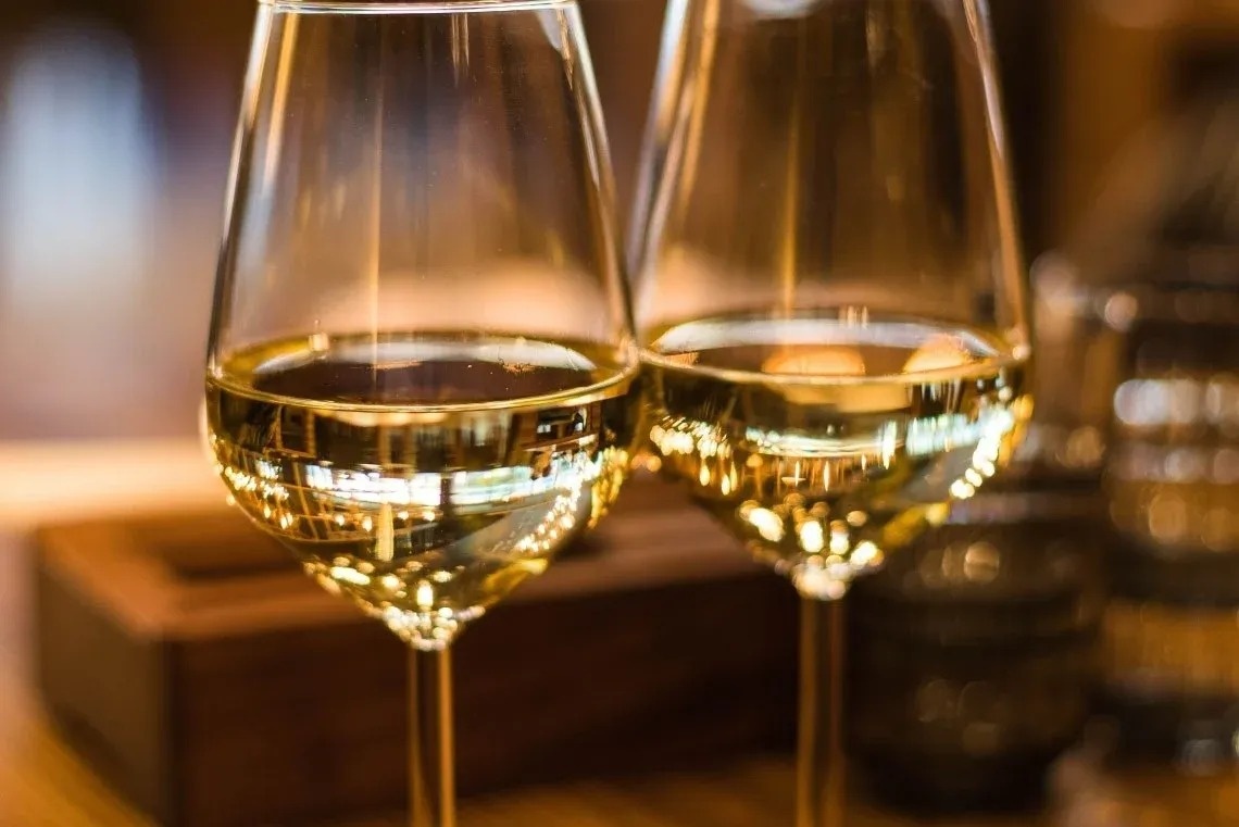 dois copos de vinho branco estão sobre uma mesa de madeira .