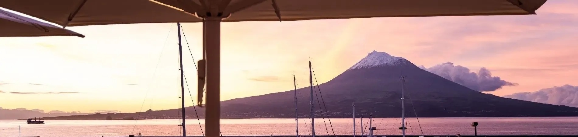 Porto de Horta ao pôr do sol, com o vulcão Pico ao fundo. Azoris Faial Garden | Website Oficial.