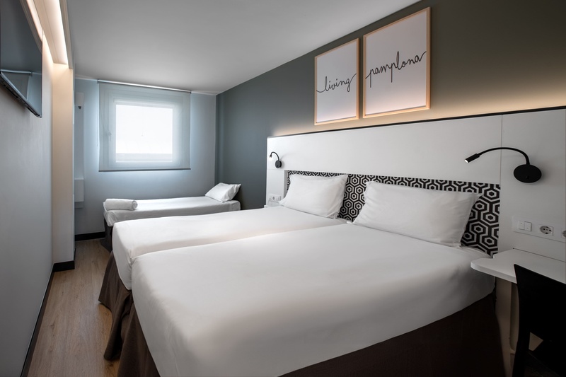 une chambre d' hôtel avec trois lits et deux affiches sur le mur qui disent loving pamplona