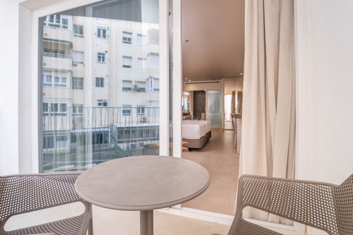a view of a hotel room from a balcony with a table and chairs
