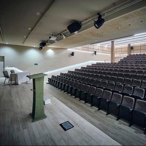 an auditorium with rows of seats and a green exit sign