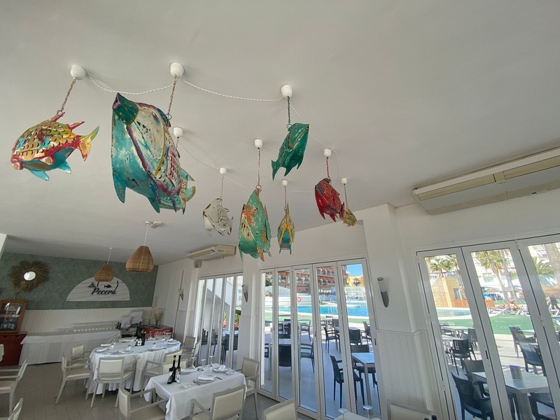 una habitación llena de mesas y sillas con un cartel en la pared que dice al pescador