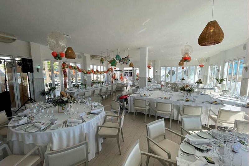 una habitación llena de mesas y sillas con globos colgando del techo