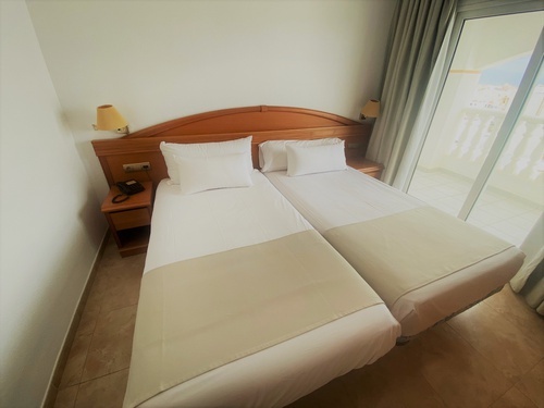 a hotel room with two beds and a sliding glass door