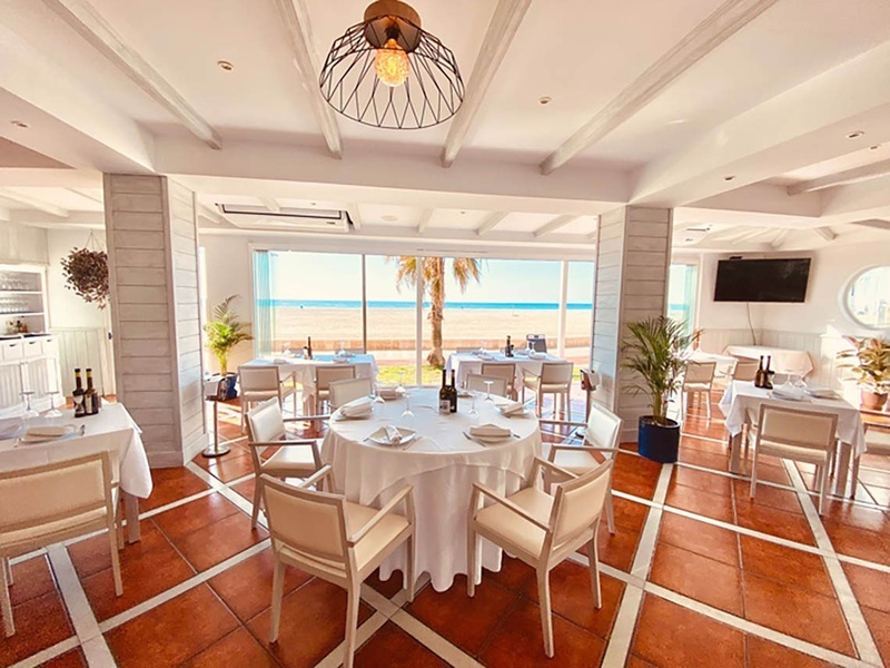 un restaurante con mesas y sillas y una vista al mar