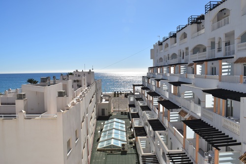 a row of white buildings with balconies overlooking the ocean