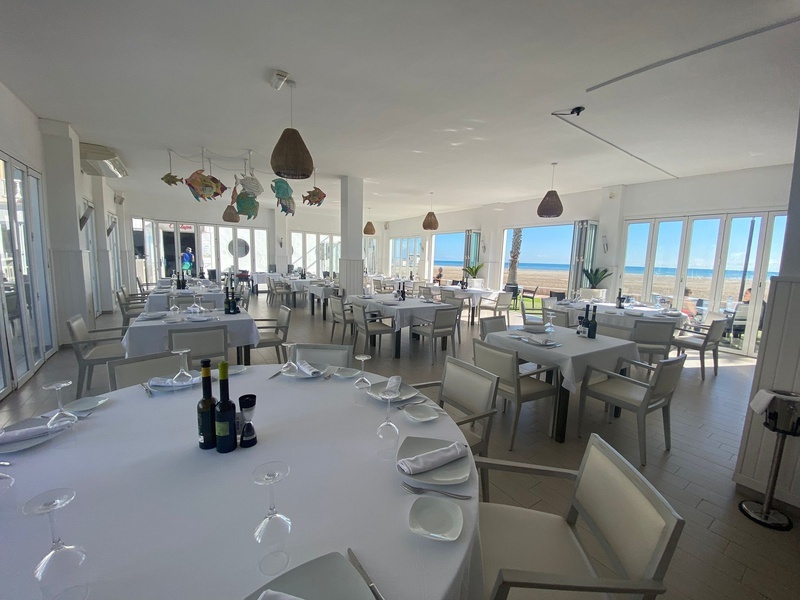 un restaurante lleno de mesas y sillas con botellas de vino