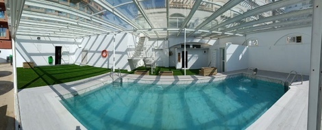 una piscina cubierta con techo de vidrio y escaleras